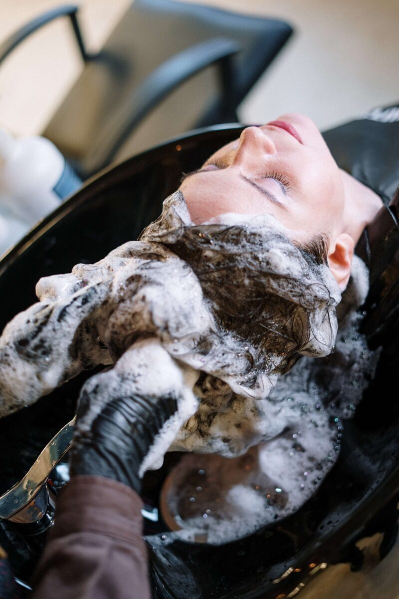 Žena leží u kadeřníka a myjí jí vlasy.