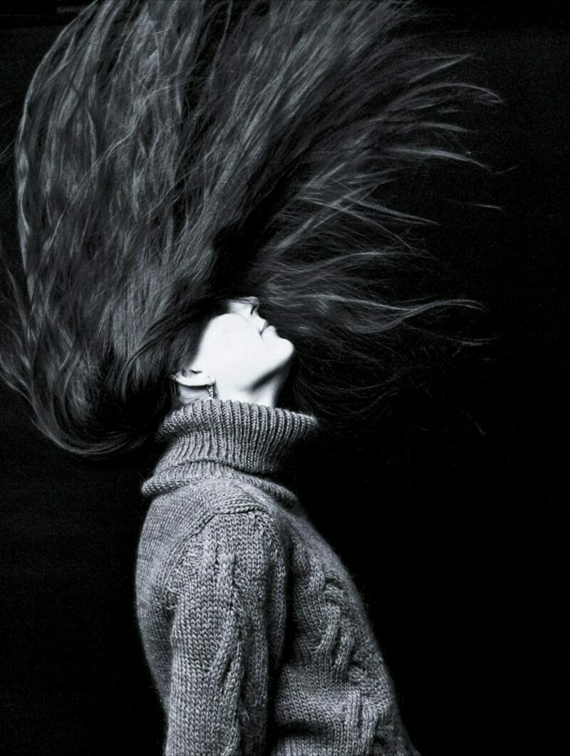 Černobílý snímek, žena zakloní hlavu tak rychle, že jí vlasy vyletí do výšky.
