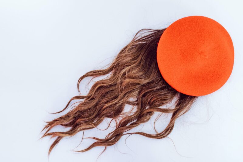 Hnědé vlasy bez hlavy, s oranžovým balónkem na ní