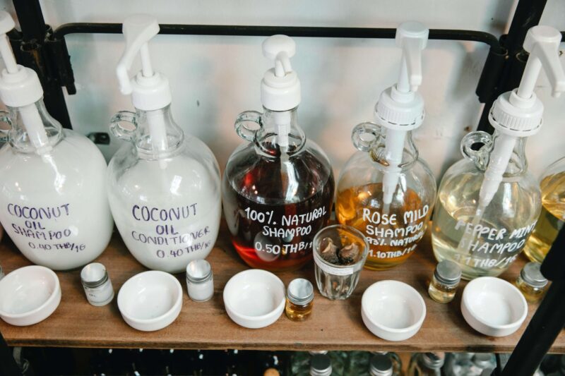 5 různých šamponů v průhledném skleněném obalu na regálu